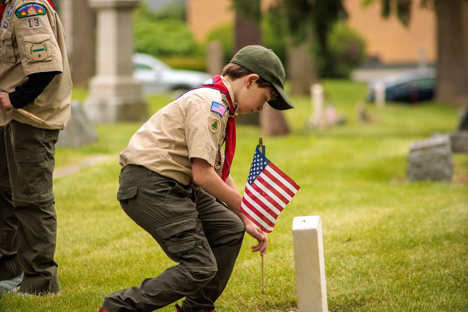 A Scout places an American flag at a veteran's grave